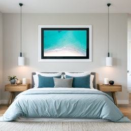 An Art Wall Room Mockup generated with AI for Print On Demand Seller. The mockup features a Coastal Style Bedroom with a framed photography print of a beautiful tropical beach from the sky hanged on the wall