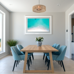 An Art Wall Room Mockup generated with AI for Print On Demand Seller. The mockup features a Coastal Style Dining room with a framed photography print of a beautiful tropical beach from the sky hanged on the wall